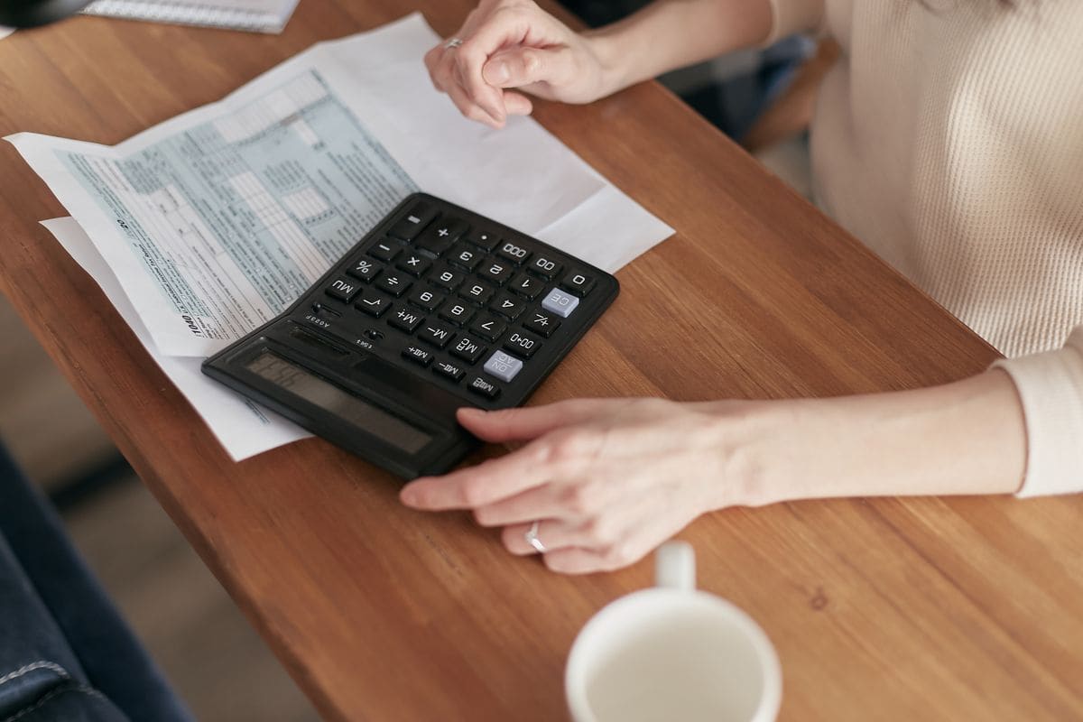Person using a calculator to manage finances at a desk
