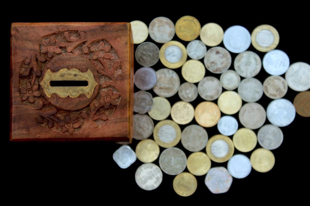 Wooden savings box beside coins