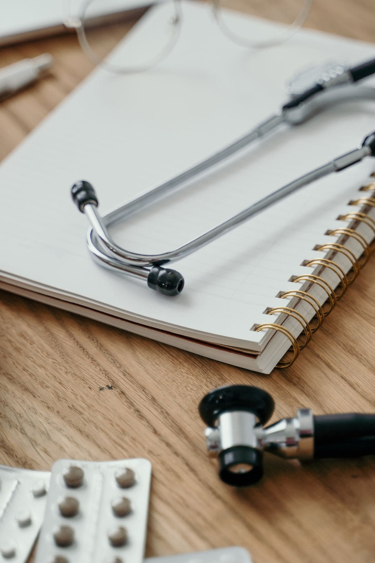 Stethoscope, notebook and medicines on a desk