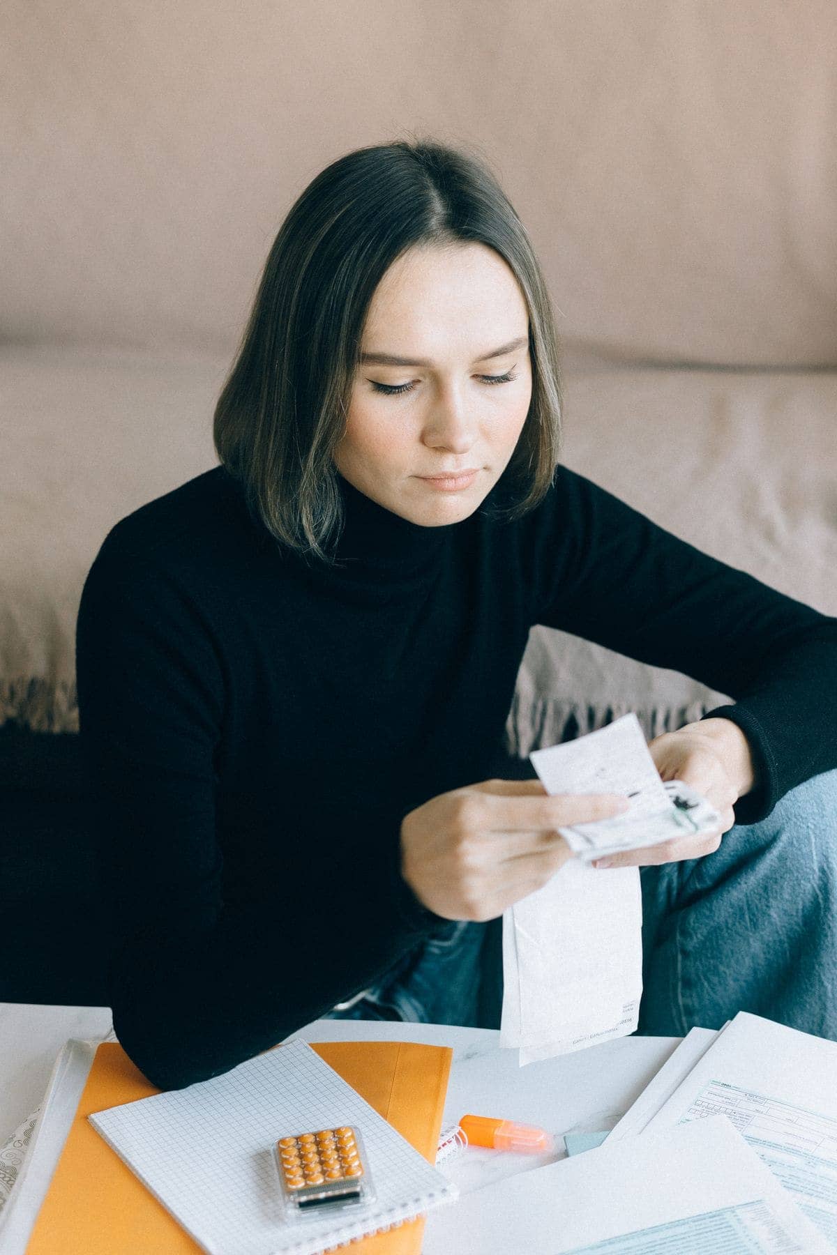 Woman reviewing bills and documents with a calculator