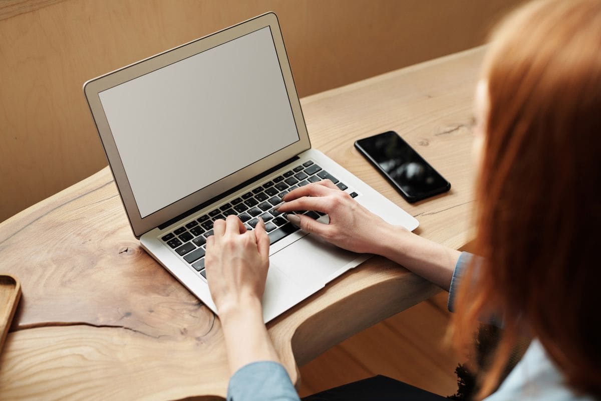 Person typing on a laptop at a wooden desk