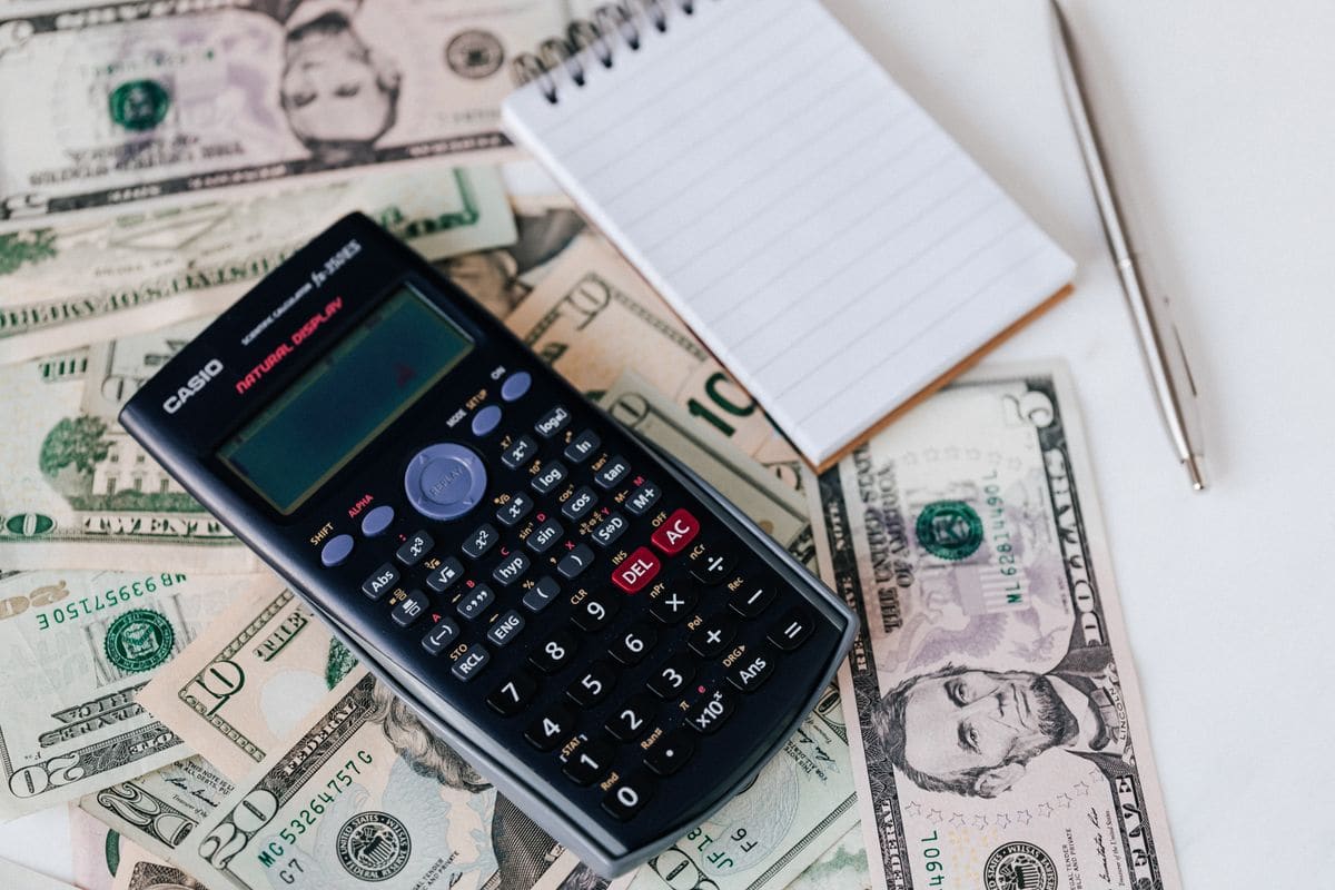 Calculator and notepad on a stack of US dollars