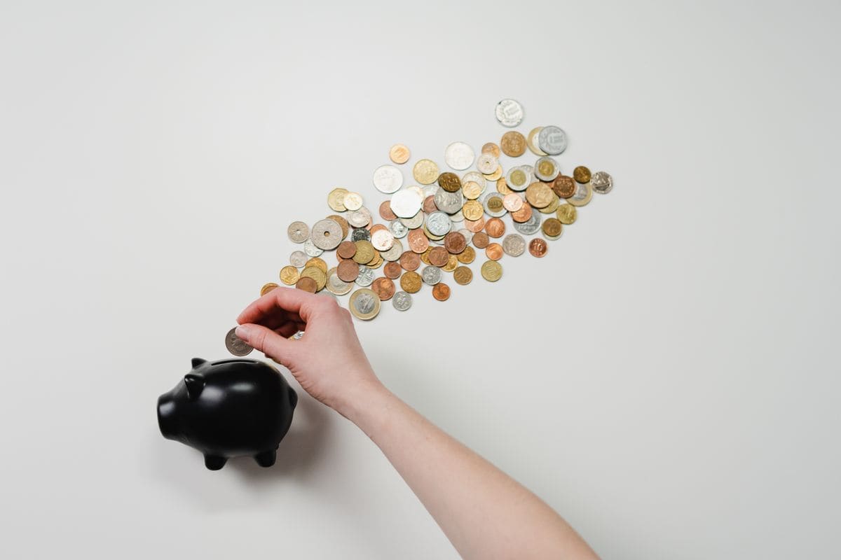 Person putting a coin into a piggy bank