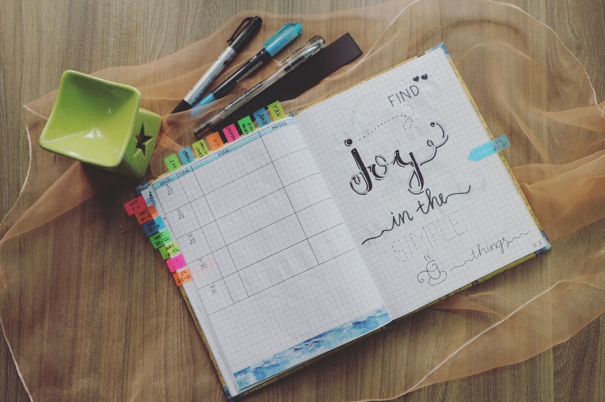 Open planner with pens on a wooden desk