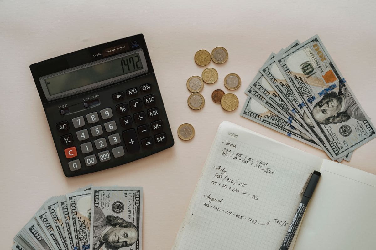 Calculator beside coins and a notebook